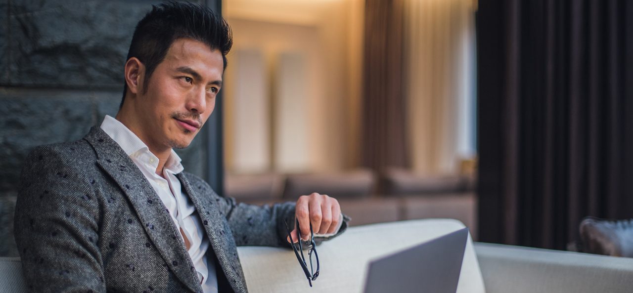 Un homme d'affaire assis sur un canapé utilisant son ordinateur